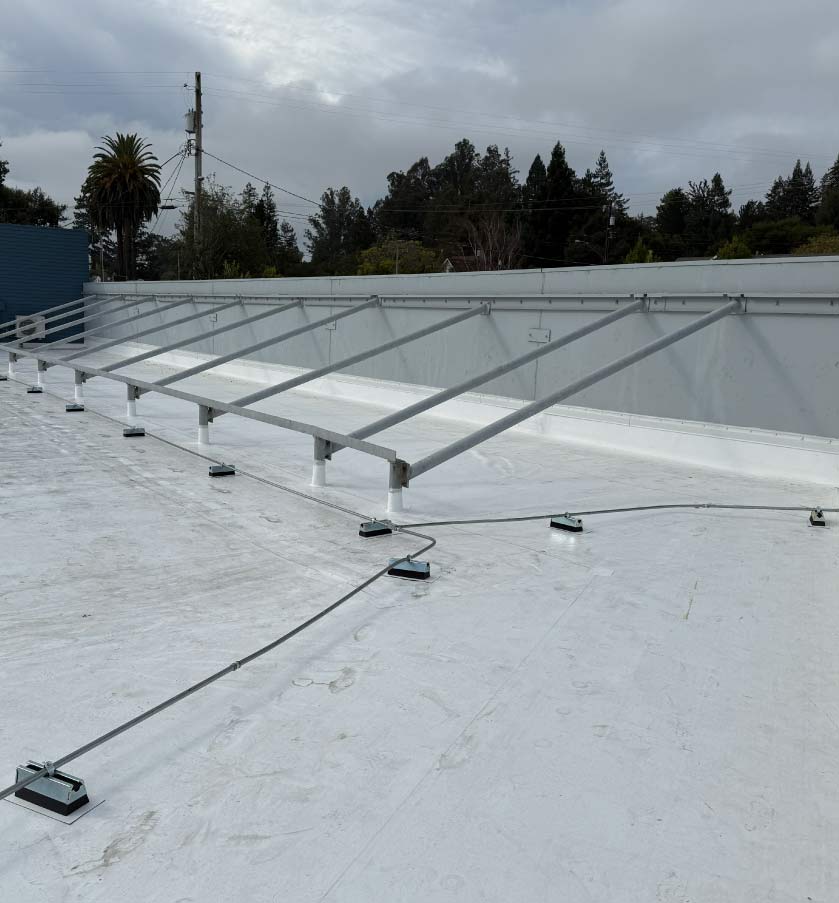 Commercial flat roof system with energy-efficient white cool roof coating and mounted metal equipment racking.