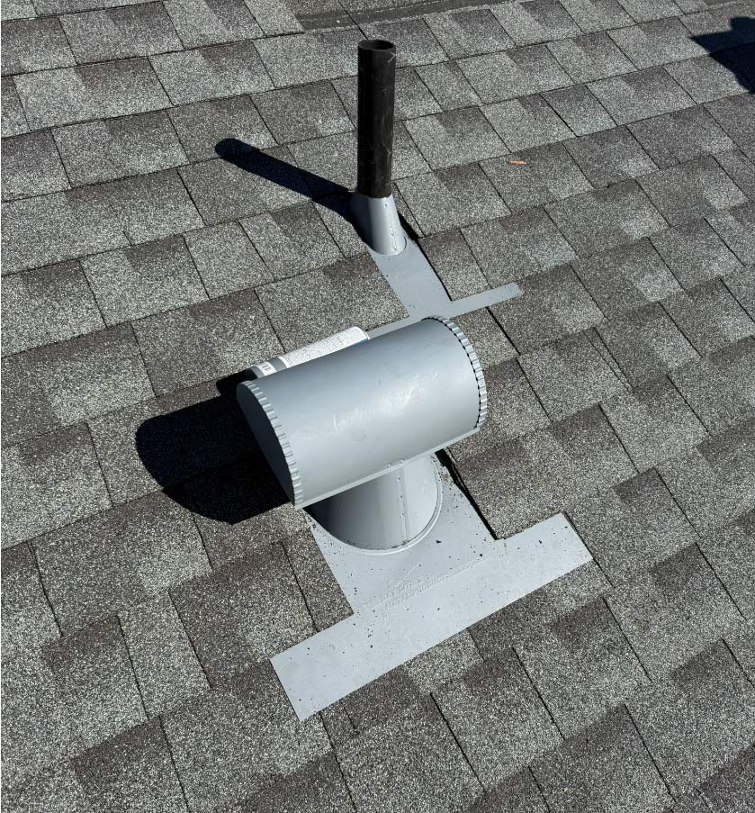 Properly installed galvanized steel roof vent pipe flashing on grey architectural asphalt shingles.